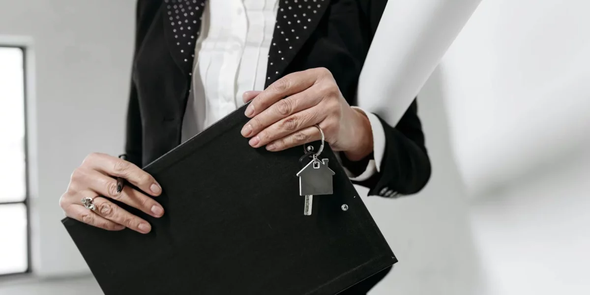 Femme en costume tenant des clés et un dossier dans un intérieur moderne — cryptomonnaies