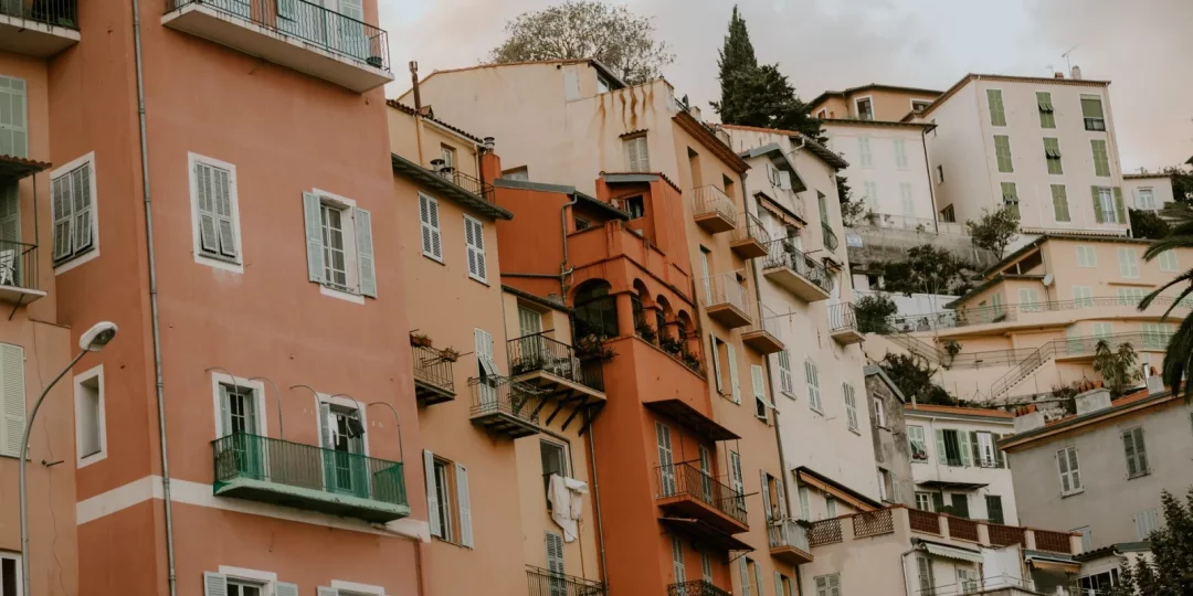 Immeubles colorés avec balcons et végétation en arrière-plan — permis-de-louer