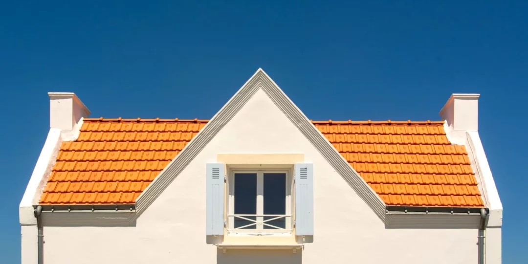 Façade d'une maison avec toit en tuiles orange sous un ciel bleu — assurance-habitation