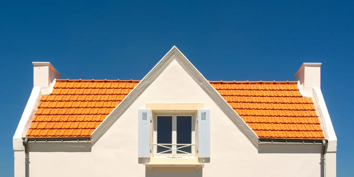 Façade d'une maison avec toit en tuiles orange sous un ciel bleu — assurance-habitation