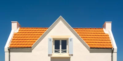 Façade d'une maison avec toit en tuiles orange sous un ciel bleu — assurance-habitation