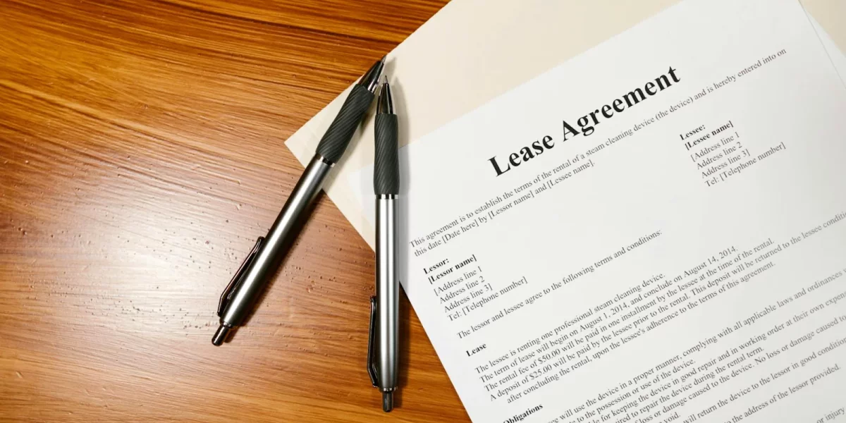 Contrat de location avec stylos sur une table en bois — bail location non meublé
