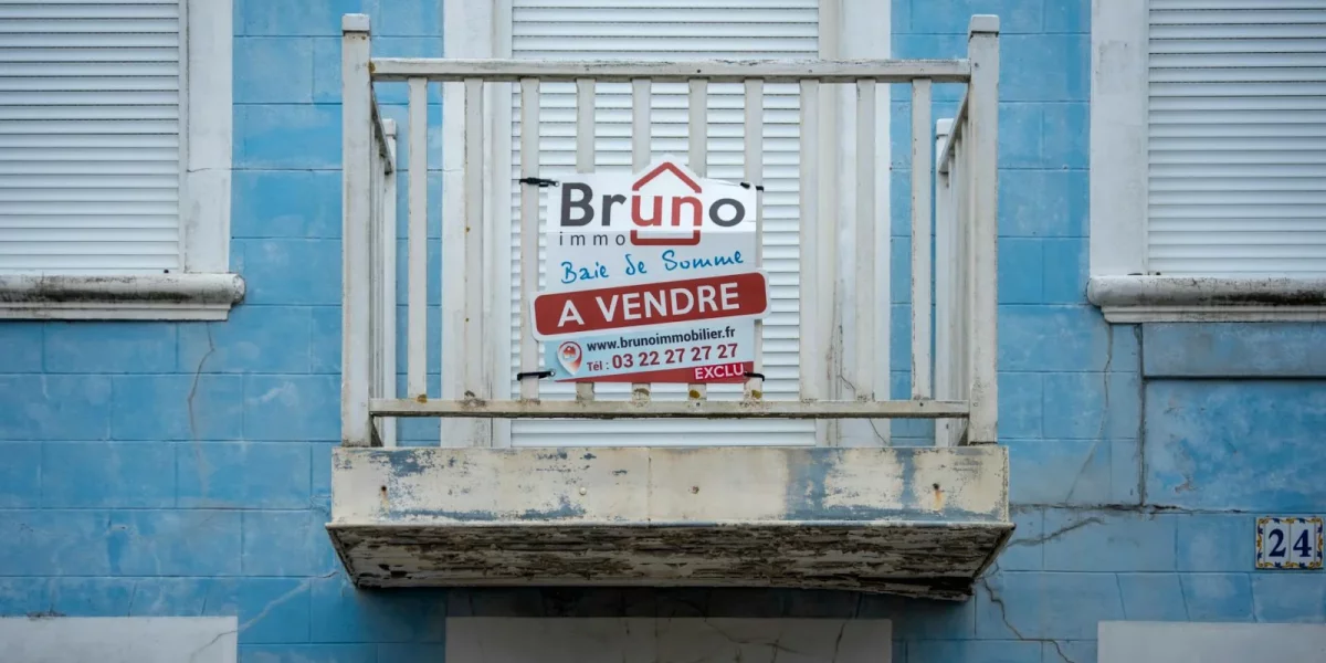 Balcon avec panneau "À vendre" sur mur bleu — barème droits de succession