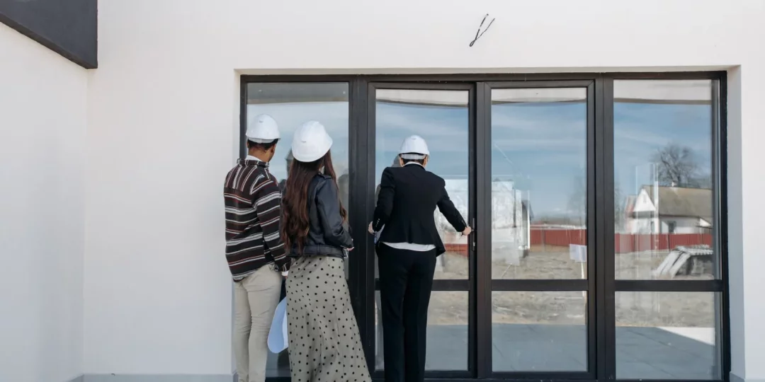 Trois personnes portant des casques observant une porte vitrée — contre-visite immobilier