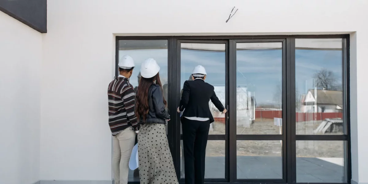 Trois personnes portant des casques observant une porte vitrée — contre-visite immobilier