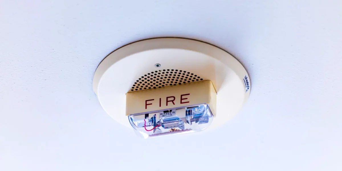 Détecteur de fumée rond fixé au plafond blanc d'un logement, équipement dont l'obligation s'impose à tout propriétaire