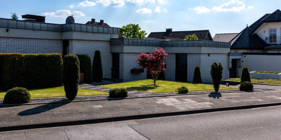 Jardin bien entretenu avec arbres et haies devant une maison moderne — distance de plantation