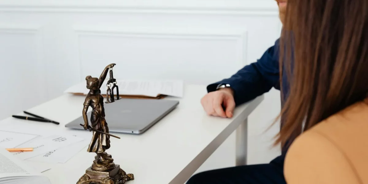 Personnes discutant autour d'une table avec une statue de la justice — droits de succession entre frère et soeur