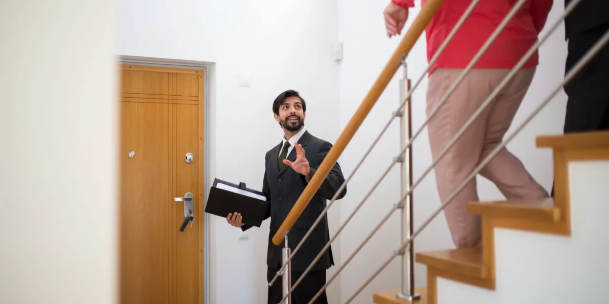 Agent immobilier montrant une maison à des clients dans un hall d'entrée — encadrement-des-loyers