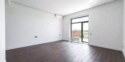 Pièce vide avec parquet et grande fenêtre donnant sur l'extérieur — état des lieux de sortie