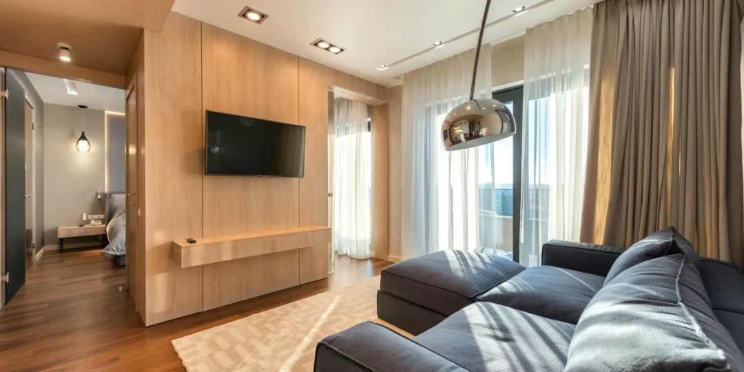 Salon moderne avec canapé et télévision, baigné de lumière — location meublée