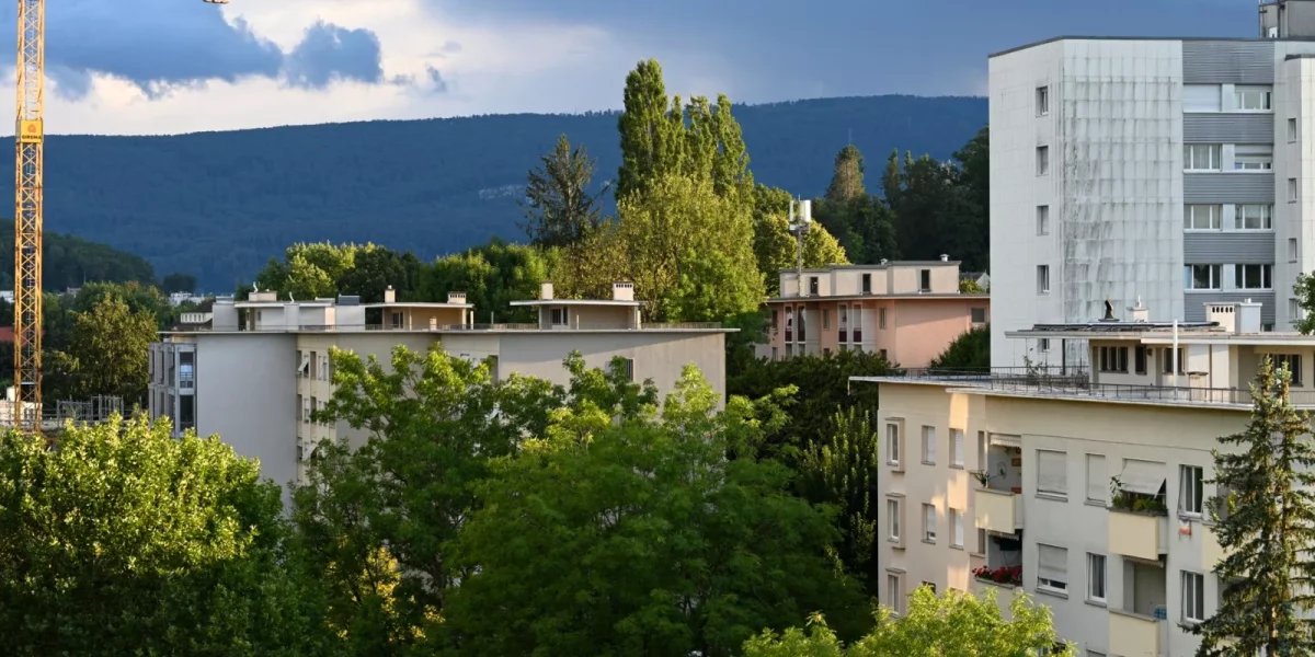 Immeubles résidentiels entourés d'arbres et de montagnes en arrière-plan — nuisances sonores