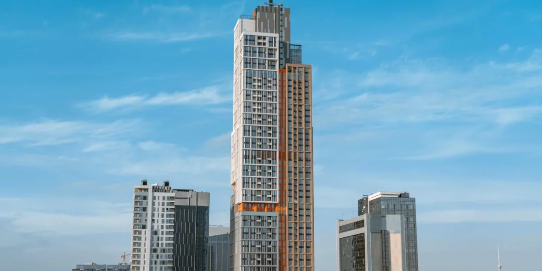 Gratte-ciel moderne sous un ciel bleu avec d'autres bâtiments environnants — economie-eau
