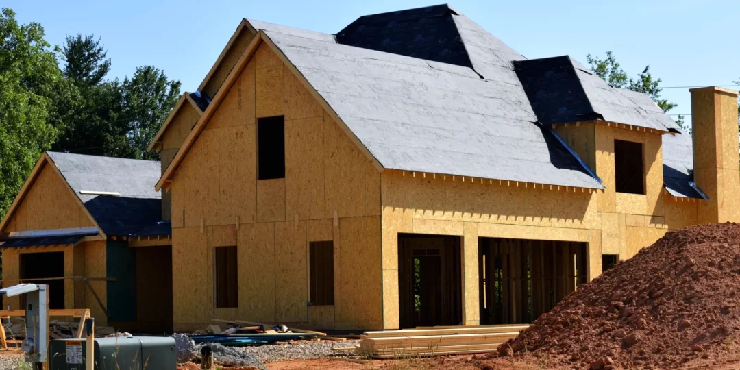 Maison en construction avec structure en bois et terrain de gravier — permis de construire