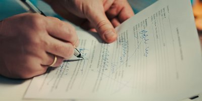 Signature d'une promesse de vente devant notaire — main tenant un stylo sur un document officiel