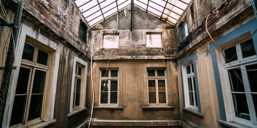 Intérieur d'un bâtiment ancien avec murs abîmés et fenêtres — auto-réhabilitation