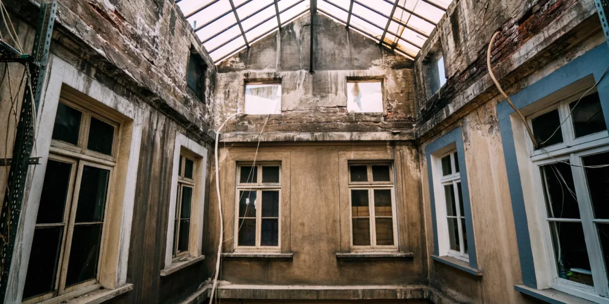 Intérieur d'un bâtiment ancien avec murs abîmés et fenêtres — auto-réhabilitation