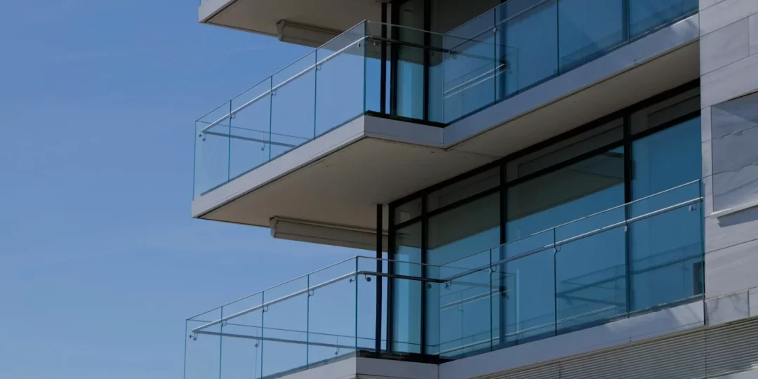 Balcons en verre d'un immeuble moderne sous un ciel bleu — copropriété