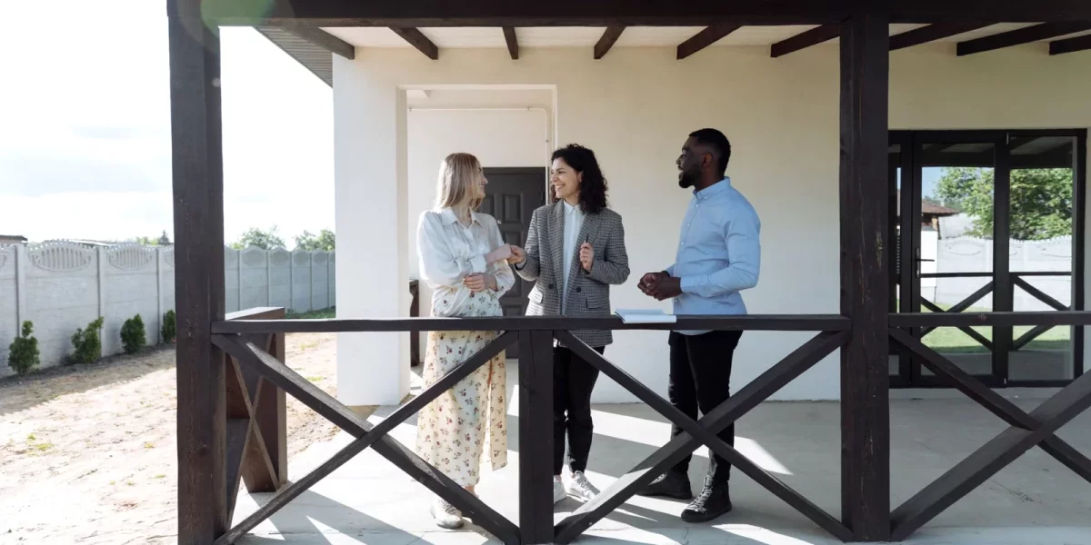 Trois personnes discutant sur une terrasse devant une maison — indivision