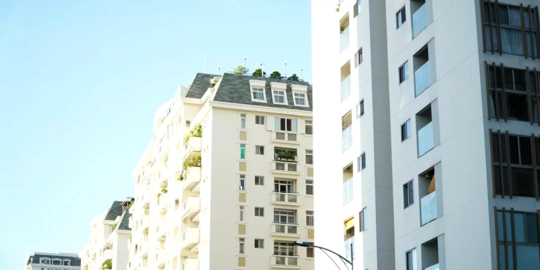 Immeubles modernes sous un ciel bleu avec balcons et végétation — copropriété