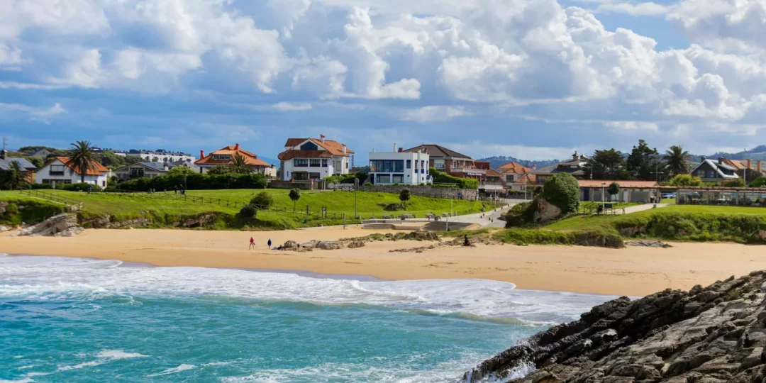 Plage avec maisons en arrière-plan et ciel nuageux — immobilier anglet
