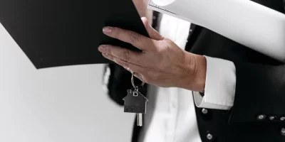 Femme tenant un dossier et des plans avec une clé en forme de maison — cession-fonds